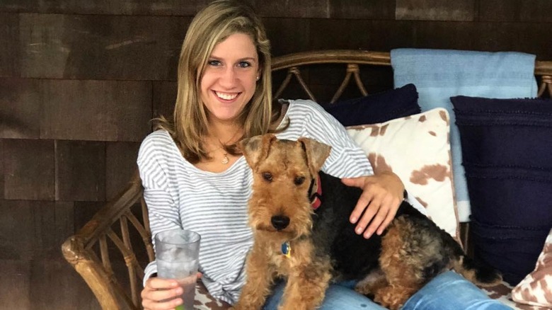 Lidey Heuck with dog on lap sitting in wicker couch