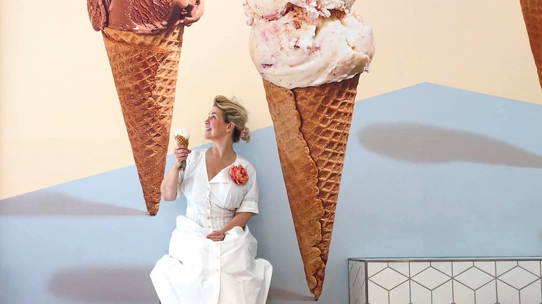 Jeni Britton Bauer sitting with a cone full of ice cream in front of a large image of ice cream cones