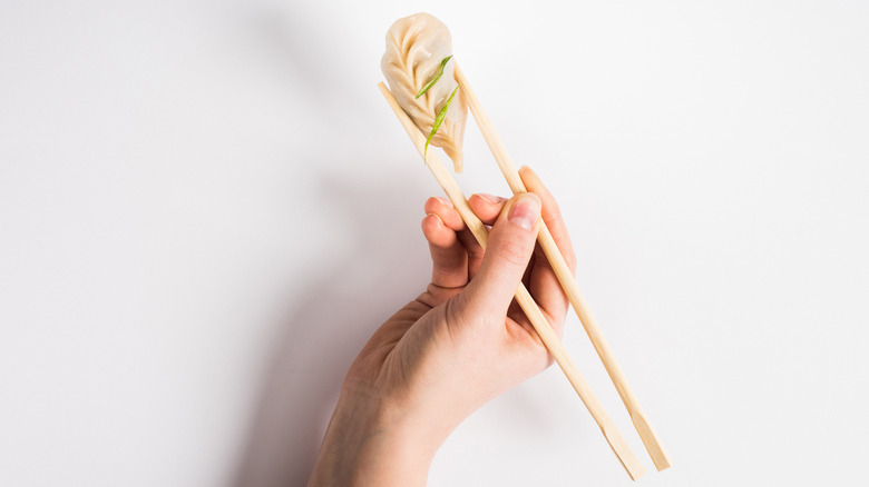 Chopsticks holding dumpling