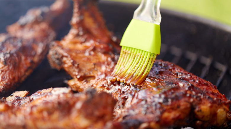 BBQ sauce being brushed on grilled chicken