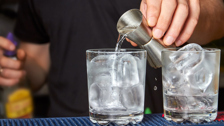 bartender pouring gin into tumblers