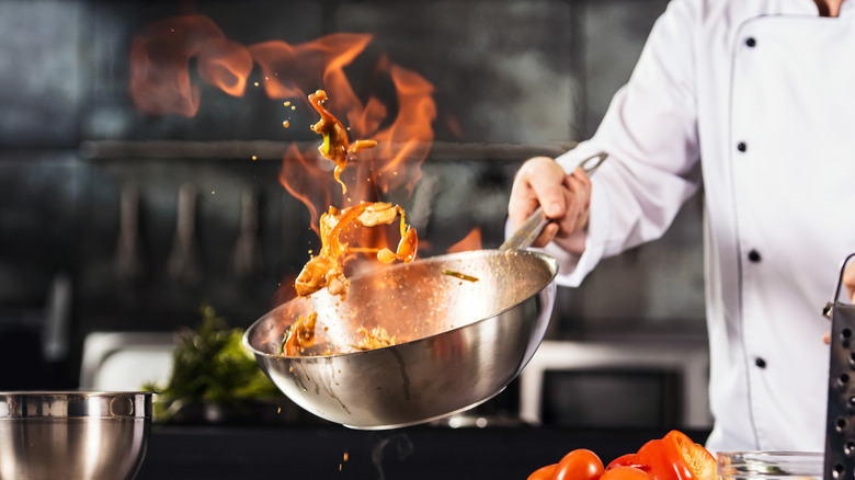 flaming pan of seafood tossed in the air