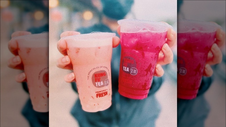 hands holding two pink Kung Fu Tea drinks