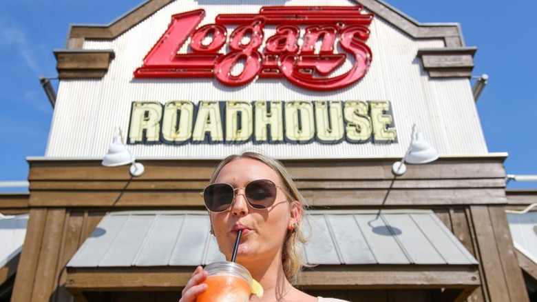 woman drinking in front of Logan's Roadhouse 