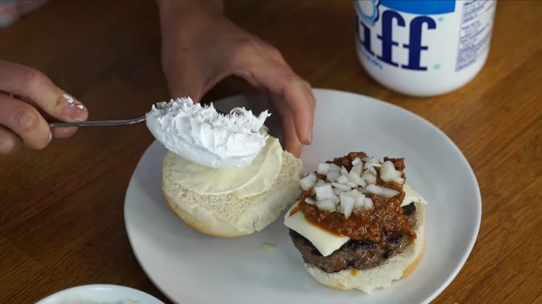 woman's hands spreading Marshmallow Fluff onto hamburger