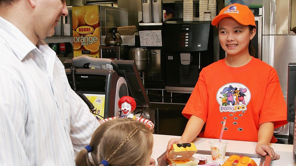 A McDonald's employee serving a tray of food