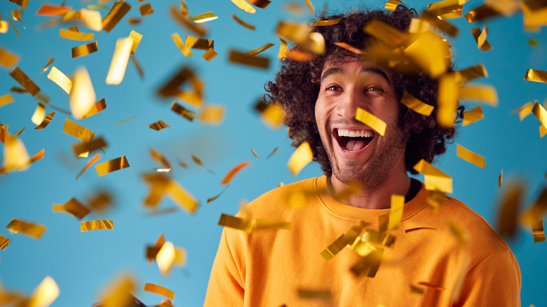 man getting showered in golden confetti