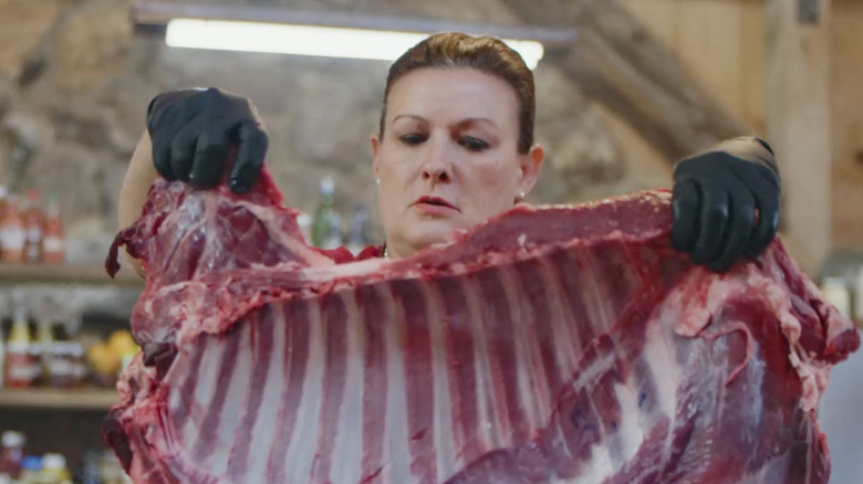 Woman holding slab of meat with gloves