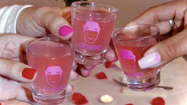 Hands holding Pink Whitney shots 