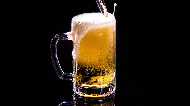 A beer mug with foam flowing over the side