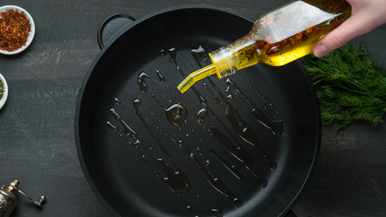 hand pouring oil into frying pan