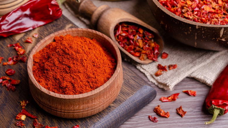 Red spices in bowl and scoop on wooden table