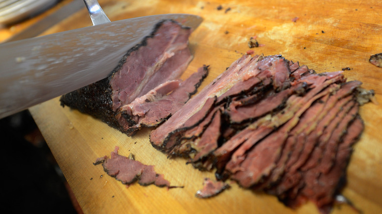 slicing pastrami on wooden board