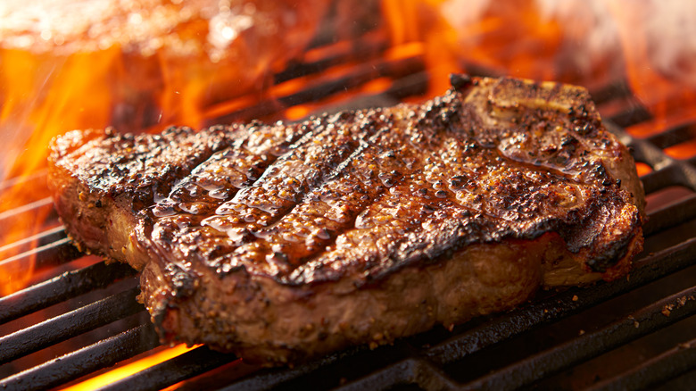 Ribeye steak on flaming grill