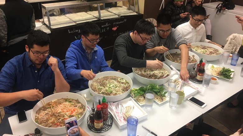4 people eating enormous bowls of pho
