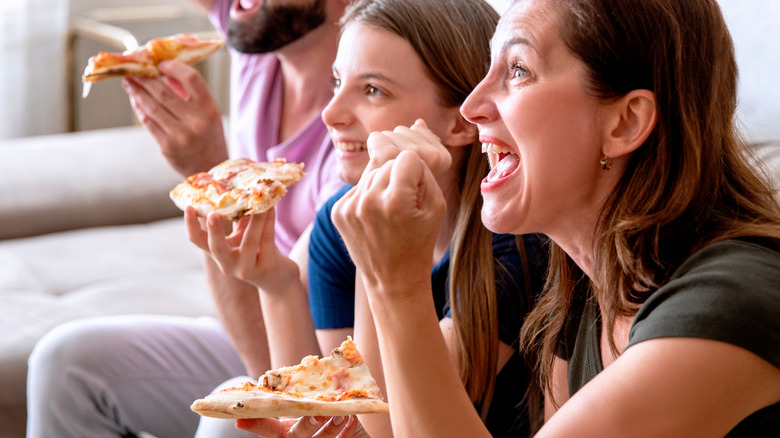 People eating pizza while watching sports on TV