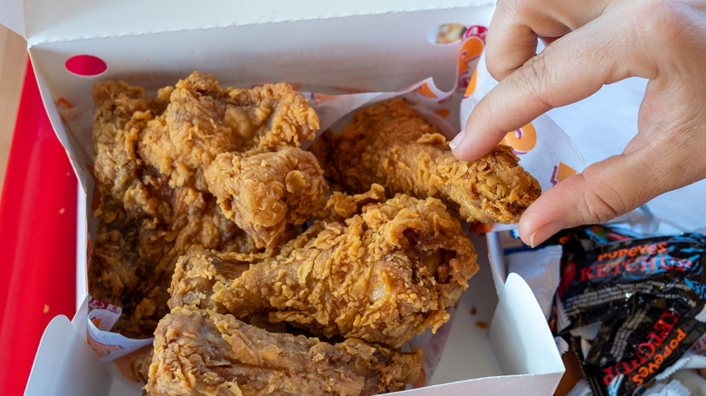 Box of Popeyes chicken with hand reaching in
