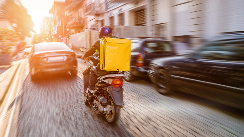 Delivery driver on driving scooter 