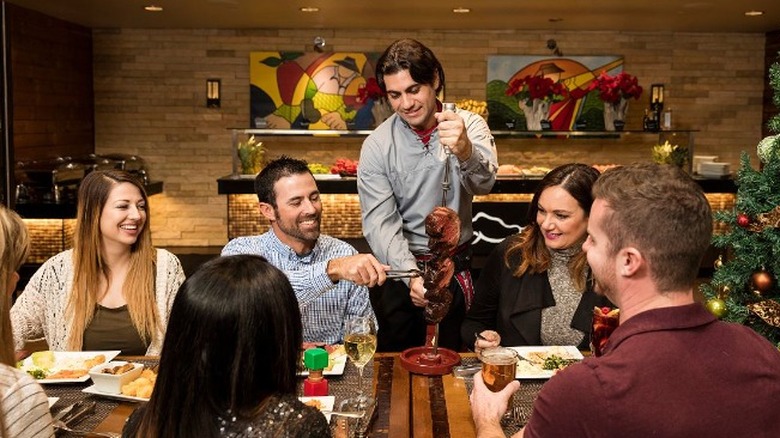 A waiter hand craving the meat for a customer at a Rodizio Grill