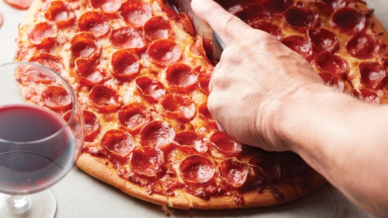 cutting a Romeo's Pizza with pepperoni