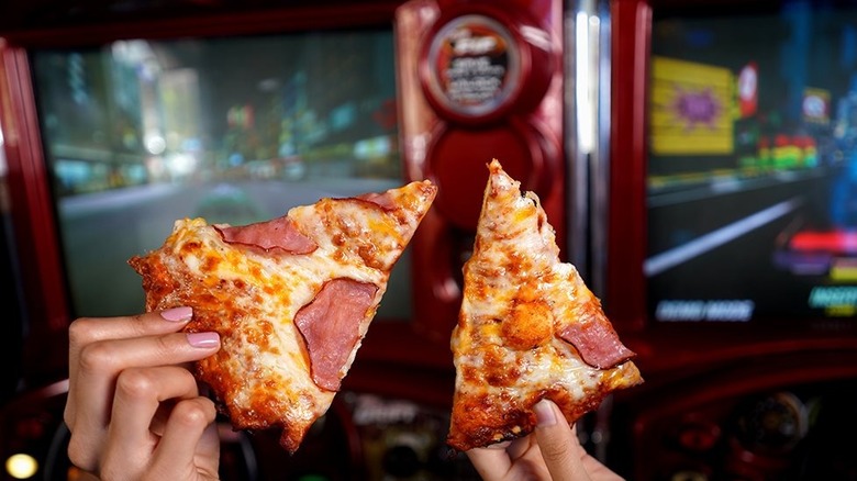 hands holding pizza slices