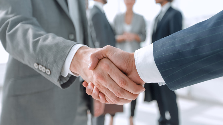 Two people in suits shaking hands. 