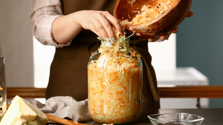 person in apron making sauerkraut