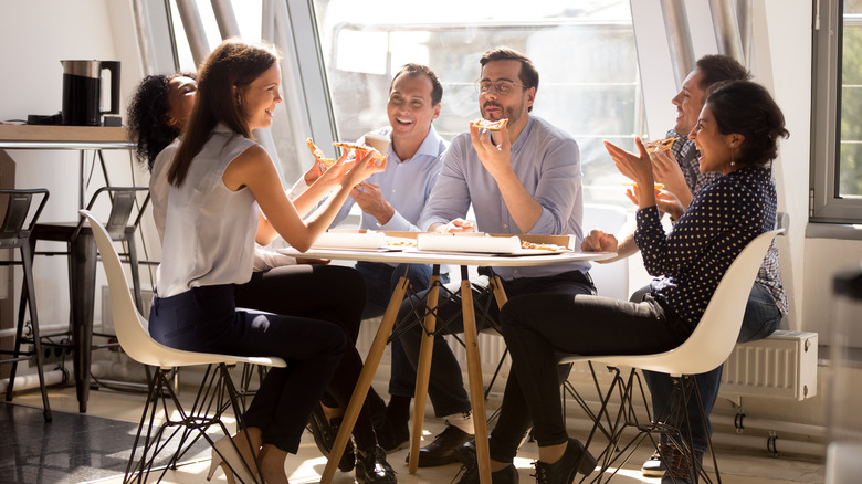 Group of people eating at a table together at work,