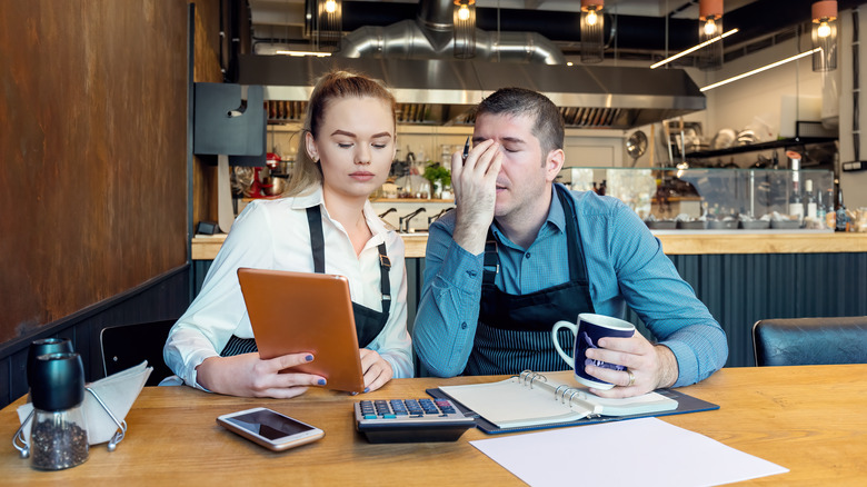 Two worried owners of a restaurant at a table