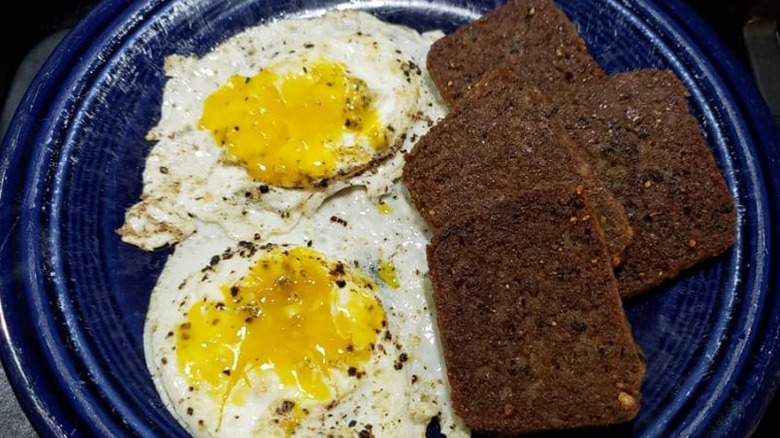Scrapple grilled crispy with two eggs on a white plate