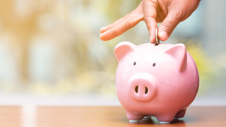 hand putting coin in piggy bank