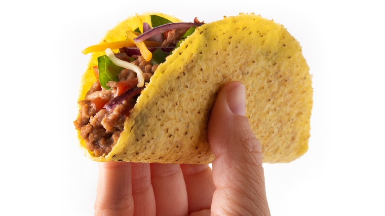 Hand holding crunchy taco