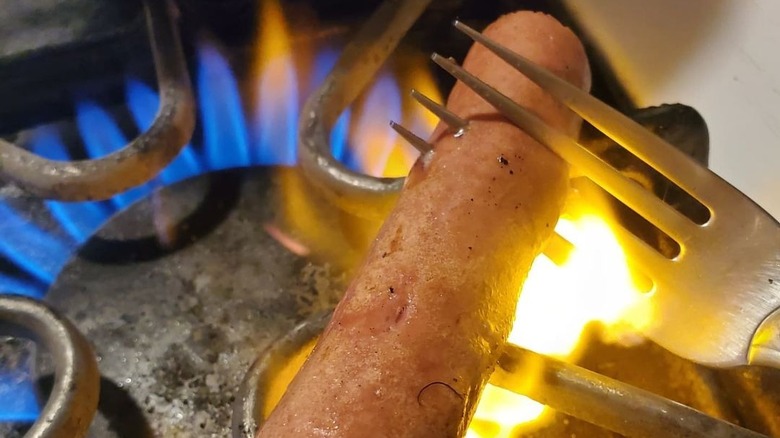 hot dog on fork roasting on the stove 