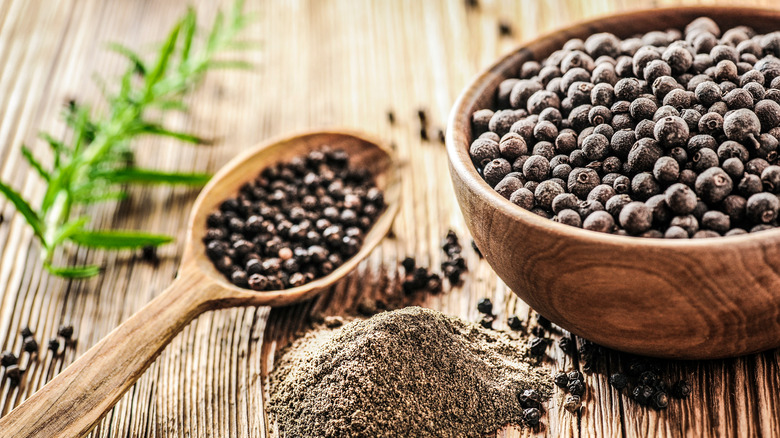 Black peppercorns in wooden bowl and spoon