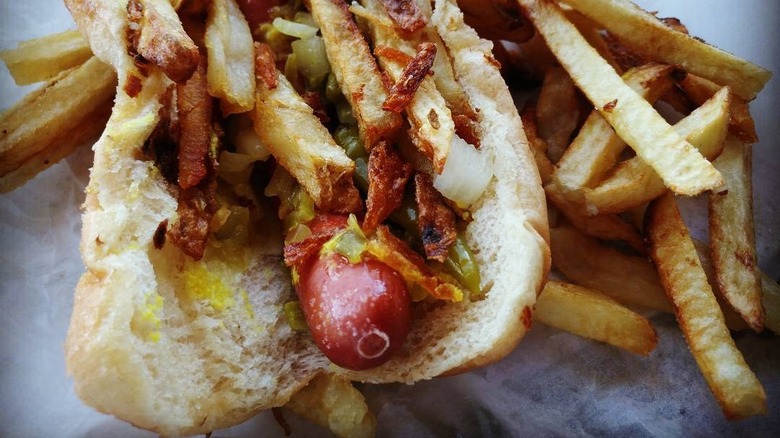 close up of Gene and Jude's Depression Dog hot dog topped with sport peppers, onions, mustard, and french fries