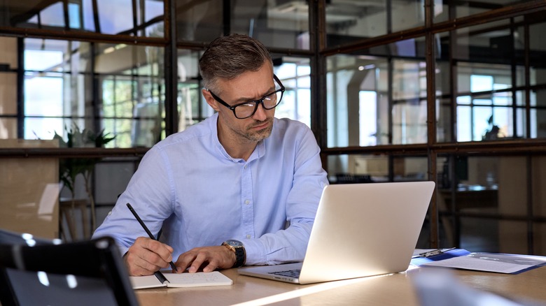 Man with laptop taking notes