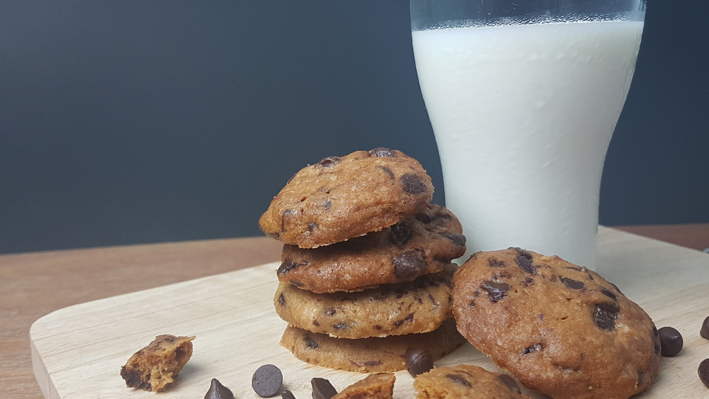 A glass of milk with a chocolate chip cookie