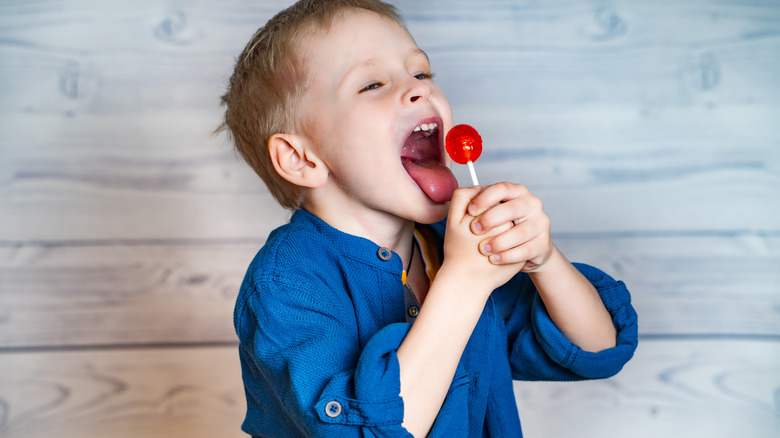 A young boy with his mouth open to lick a lollipop