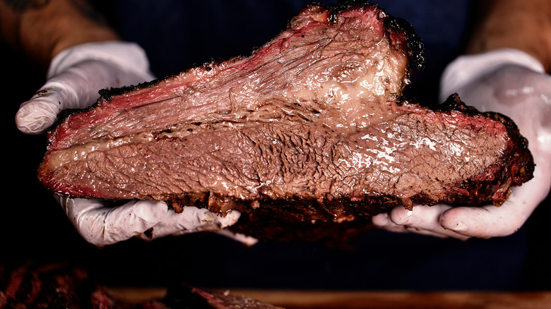 hands holding smoked brisket