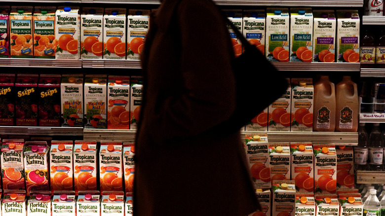 woman passing aisle of Tropicana cartons