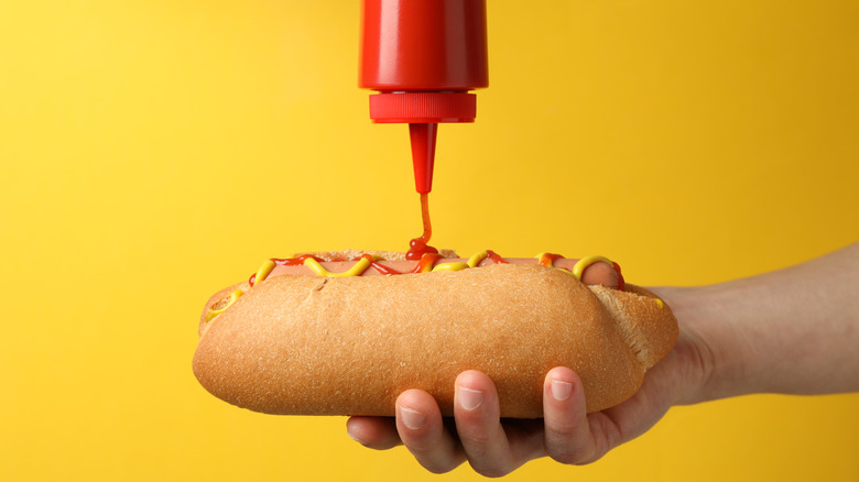 squeezing ketchup on hot dog