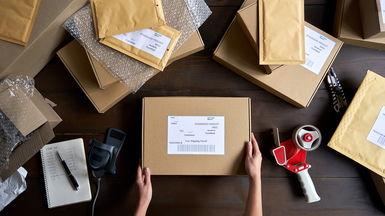 Packing material including bubble wrap, cardboard boxes, and envelopes on a table.