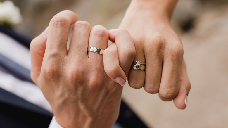 Married couple holding hands rings