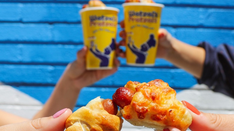 two people toasting wetzel's pretzel dogs