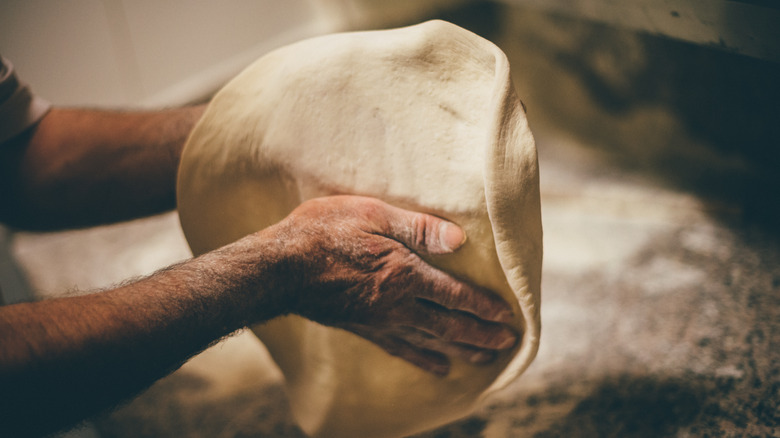 Pizza dough being thrown by hand