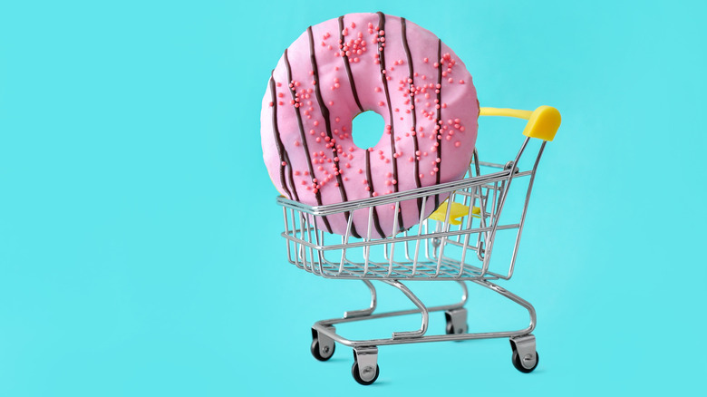 Shopping cart holding a donut against blue background