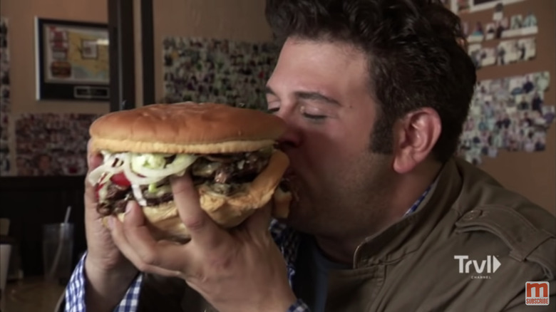 Adam Richman eating an enormous hamburger