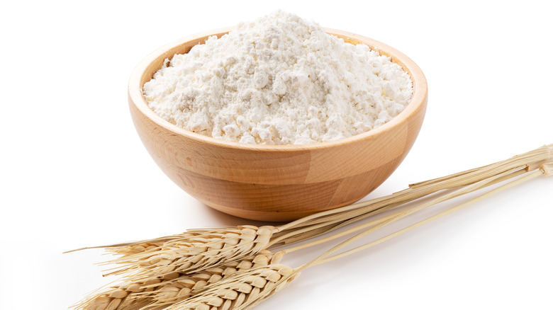 Flour in wooden bowl with wheat 