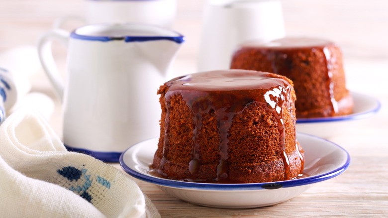 Sticky toffee puddings in dishes with sauce pitcher and napkin