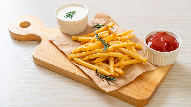 French fried on wooden board with mayo and ketchup